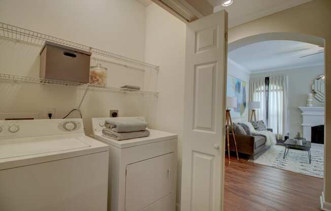 a laundry room with a washer and dryer and a living room in the background