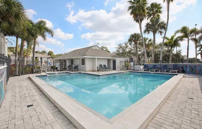 A pool surrounded by palm trees and a white building.