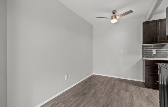 a living room with white walls and a ceiling fan