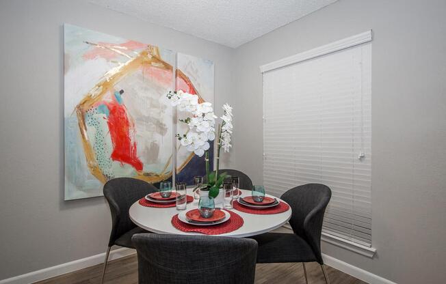 a dining room with a table and chairs and a painting on the wall