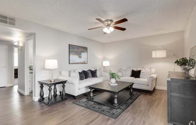 A living room with a white couch, a coffee table, and a ceiling fan.