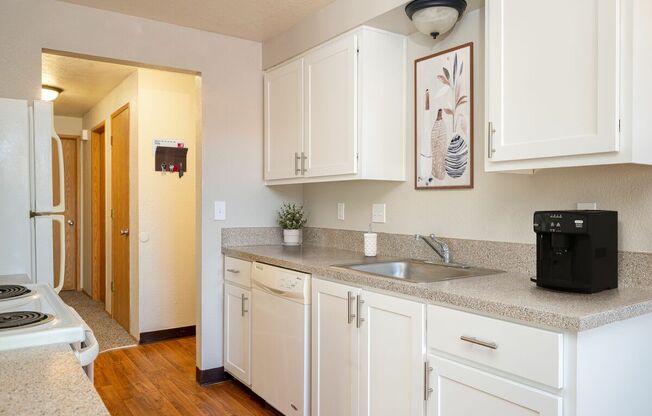A modern kitchen with white cabinets and a black coffee maker.