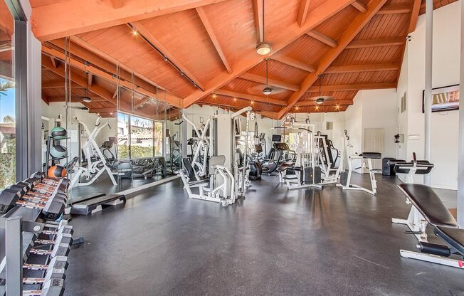 a gym with a wooden ceiling and weights on the floor