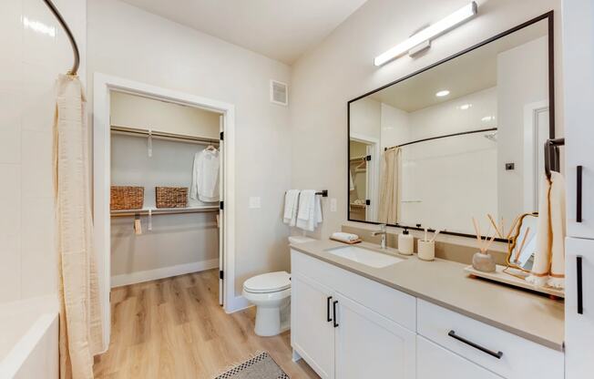 A bathroom with a toilet, sink, and mirror.