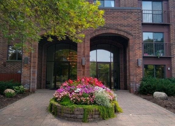 a large brick building with a flower garden in front of it