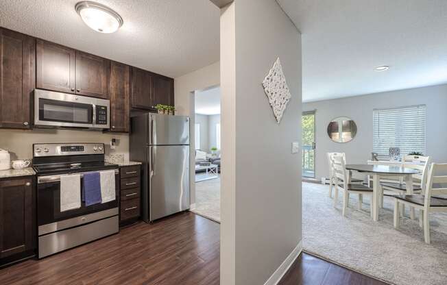 a kitchen with stainless steel appliances and a dining room with a table and chairs