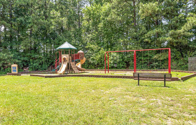 A playground with a red swing set and a green canopy.