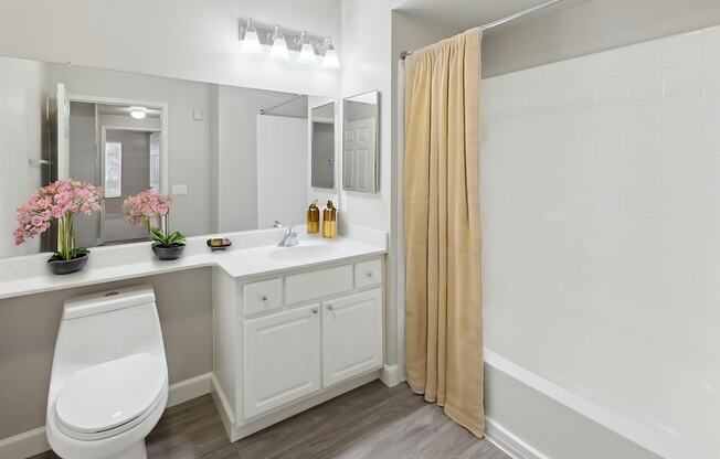 A white bathroom with a toilet, sink, and mirror.