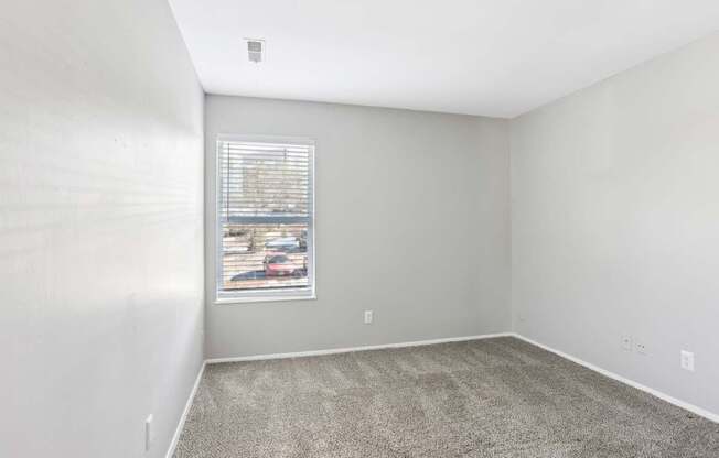A room with a carpeted floor and a window with blinds.