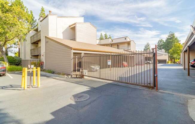 A gated entrance to a parking lot with a building in the background.