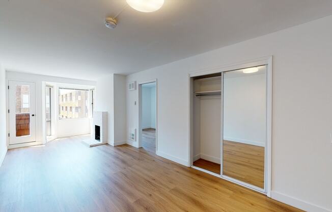 a bedroom with a large mirror and hardwood floors