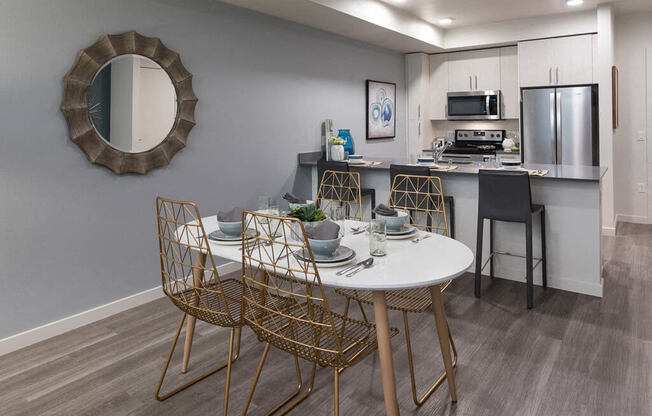 A modern dining area with a round mirror and a white table. at Ravello Apartments, Redmond, WA, 98052