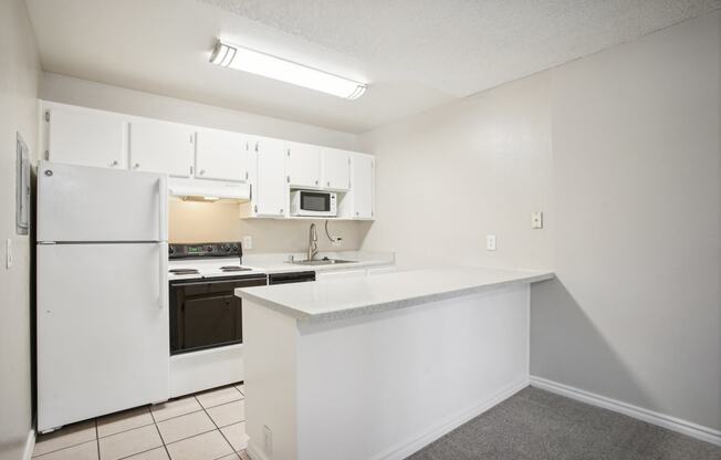 an empty kitchen with a white counter top and a refrigerator