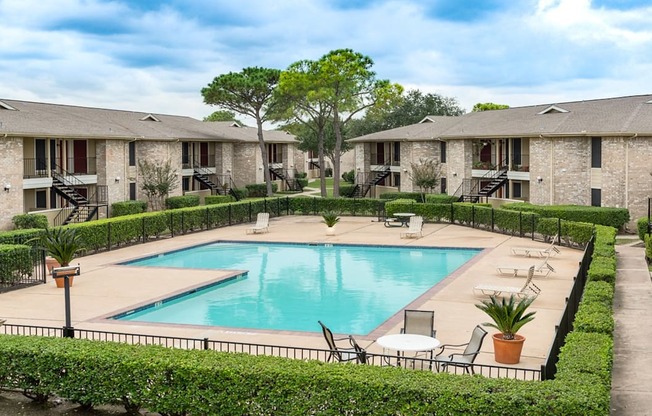 a swimming pool with chairs around it in front of apartments