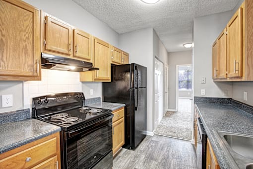 A kitchen with black appliances and wooden cabinets.