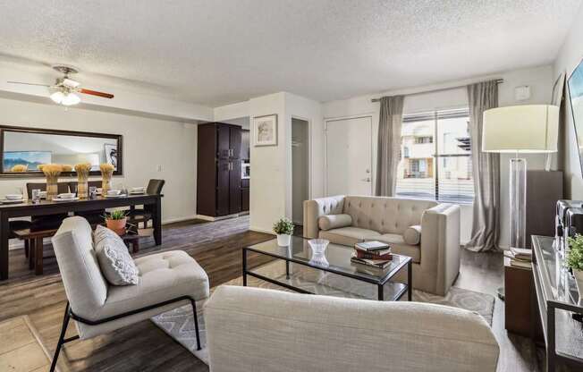 A living room with a beige couch, a glass coffee table, and a chair.