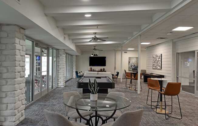 A modern dining room with a glass table surrounded by grey chairs.