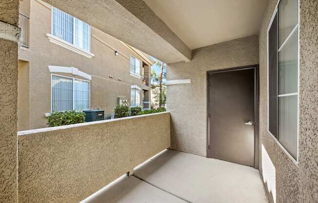 A balcony with a door and a wall with a window.