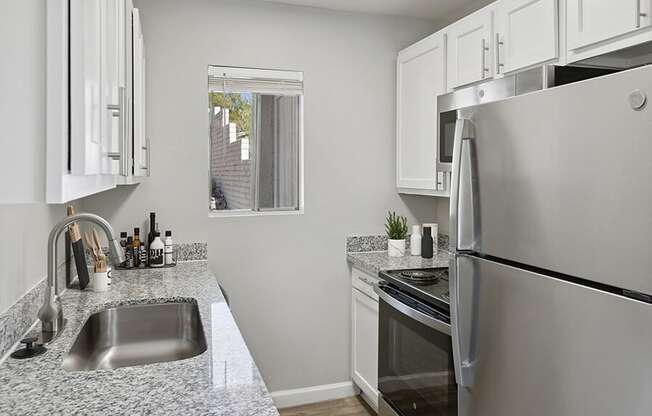 Model Kitchen with White Cabinets and Wood-Style Flooring at Hilands Apartments in Tucson, AZ.