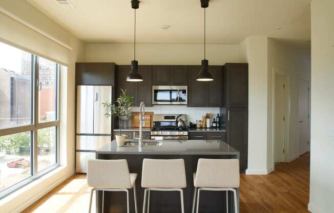 a large kitchen with black cabinets and a counter with four chairs