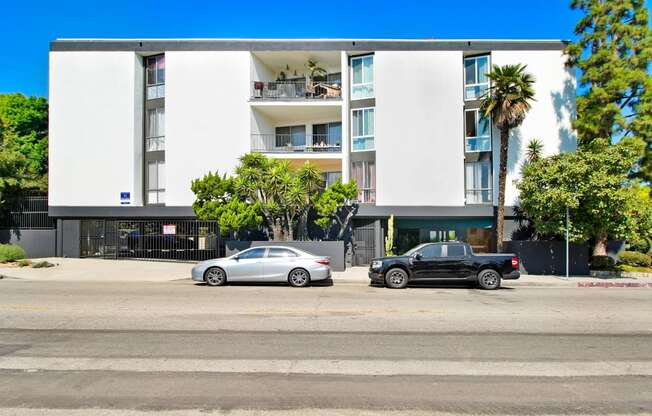 an apartment building with two cars parked in front of it