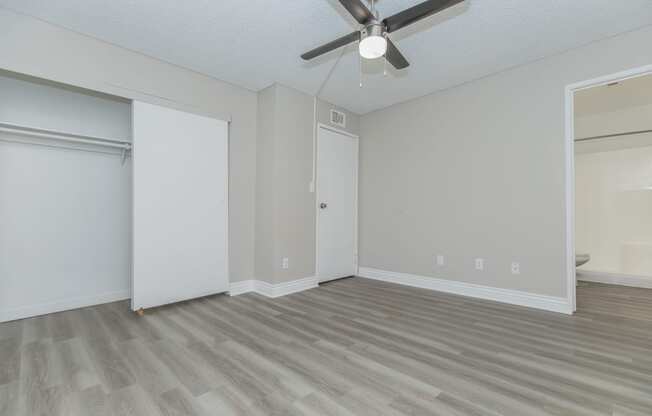 an empty bedroom with a ceiling fan and a closet