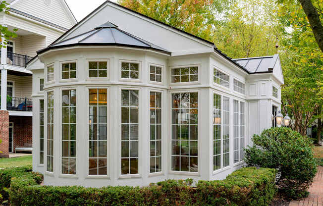 A white house with a black roof and a glass wall.