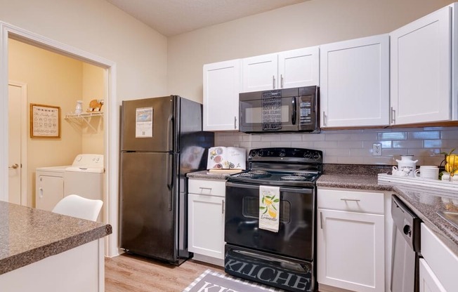 a kitchen with white cabinets and black appliances