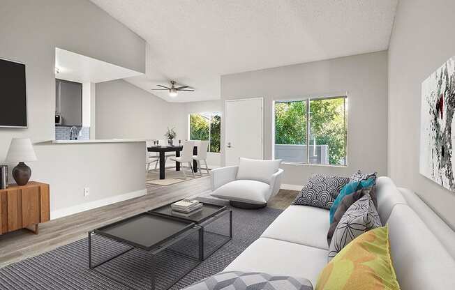 Hardwood floored living room with large windows and view of kitchen.