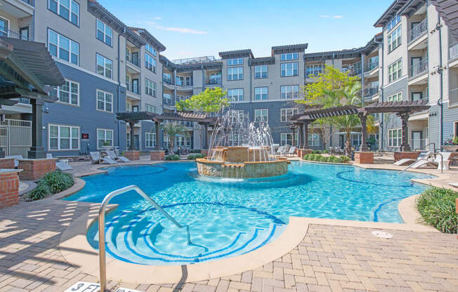 a swimming pool with a fountain in front of an apartment building