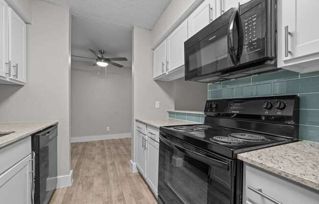 A kitchen with black appliances and white cabinets.