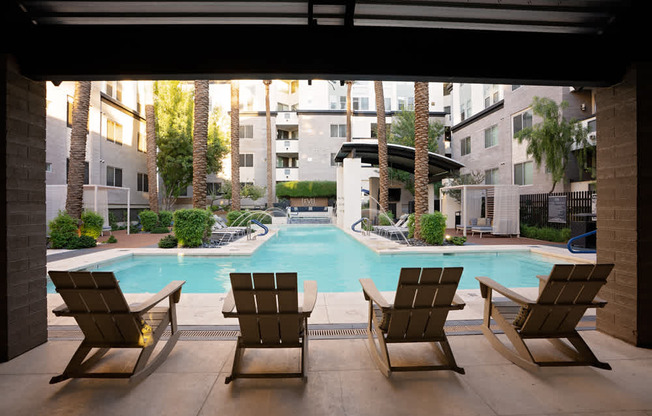 Three lounge chairs are positioned in front of a pool.