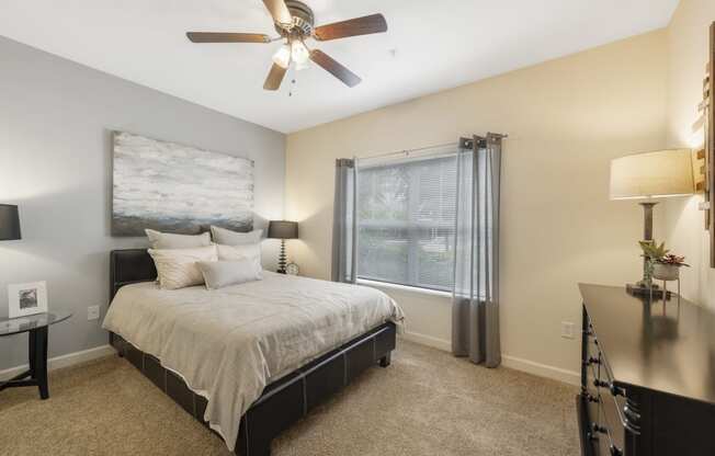 a bedroom with a bed and a window with a ceiling fan