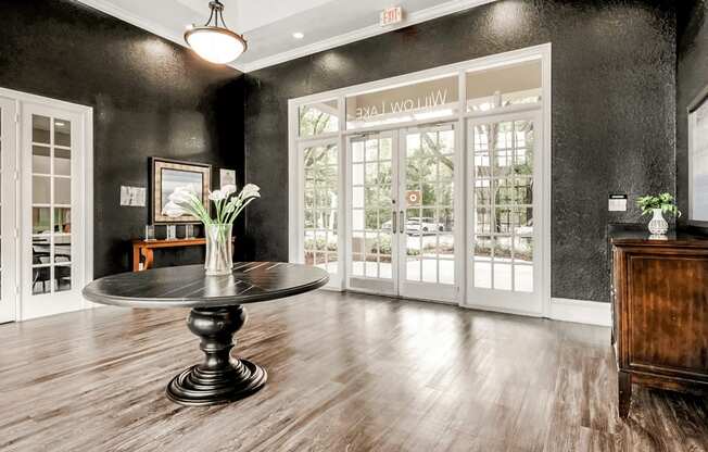 Clubhouse interior entryway with dark colored walls, brown dresser, black table with floral decor