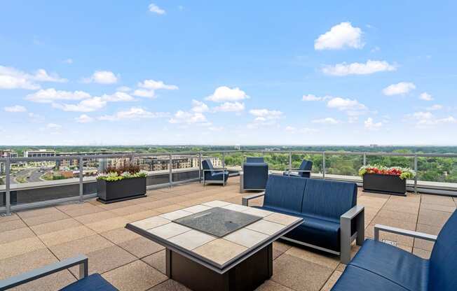 an outdoor patio with blue chairs and a firepit with a view of the city