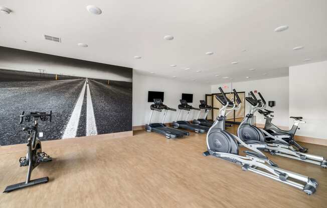 a gym with treadmills and dumbbells on a wood floor