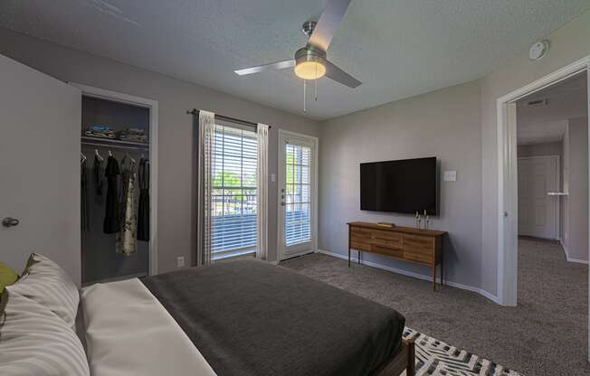 A bedroom with a bed, a dresser, a TV and a ceiling fan.