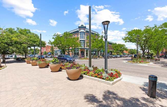 A sunny day in a town square with a row of flower pots and a street lamp.
