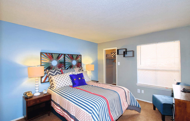 A bedroom with a bed, nightstand, and window.