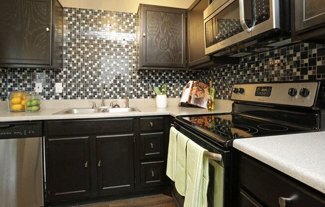 a kitchen with black cabinets and a stove and a sink