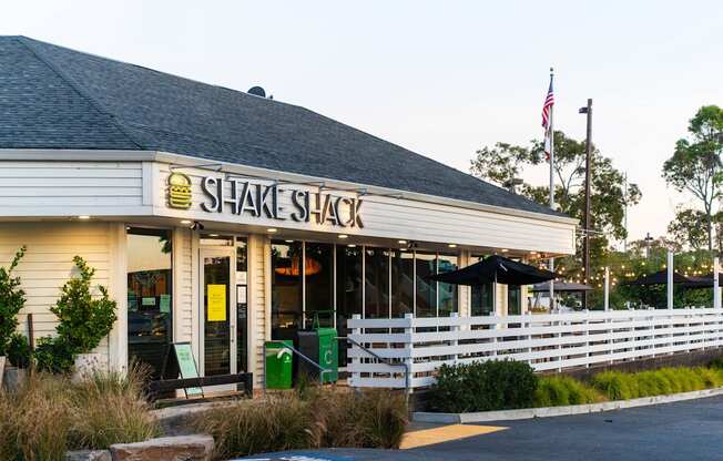 A Shake Shack restaurant with a white picket fence in front.