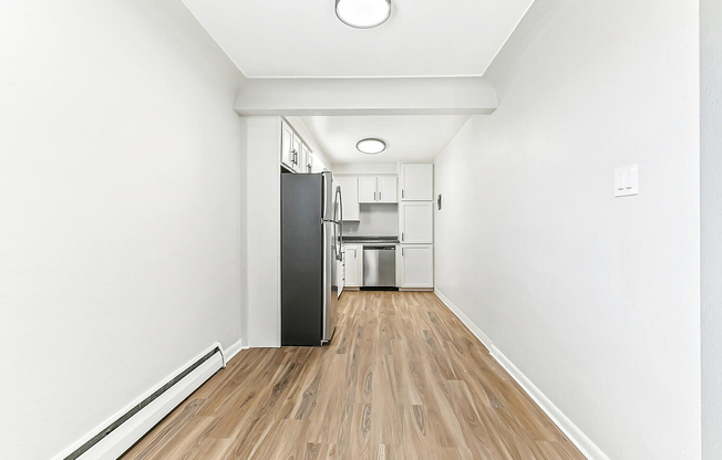 Sleek narrow kitchen with modern stainless steel appliances and elegant light wood flooring.