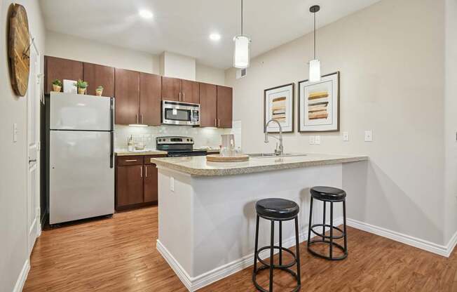 A kitchen with a white island and two black stools.