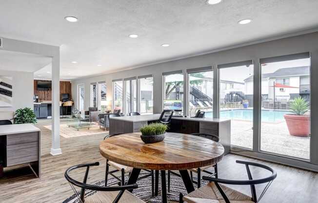 a room with a table and chairs and a pool in the background