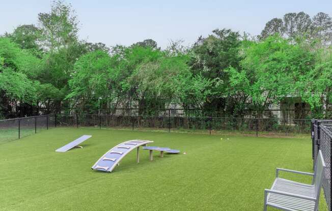 a large grassy area with a fence and lounge chairs