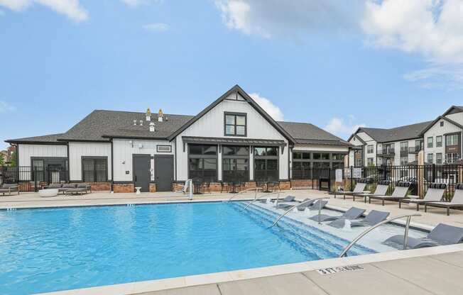 a large swimming pool with lounge chairs in front of a building