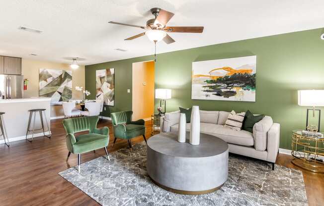 a living room with green walls and a white couch and green chairs at Crossgates Apartment Homes, Starkville, MS