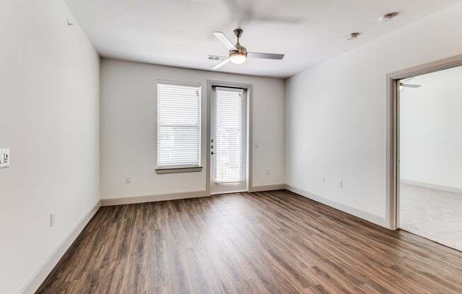 A room with a ceiling fan and sliding glass doors.