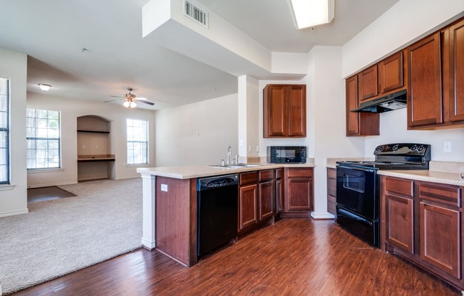 an empty kitchen with wooden cabinets and black appliances