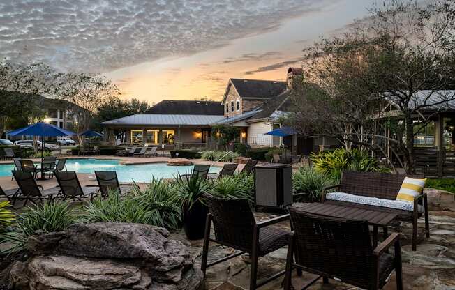 A poolside patio with chairs and a table.